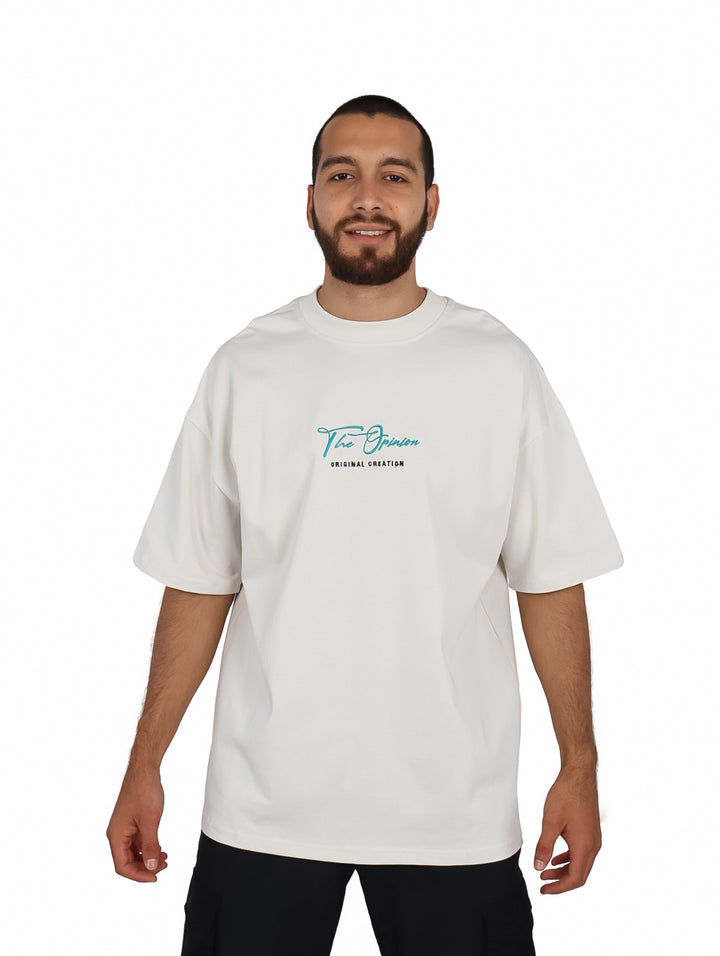 Hombre vistiendo playera oversize color beige con logotipo pequeño en el pecho.