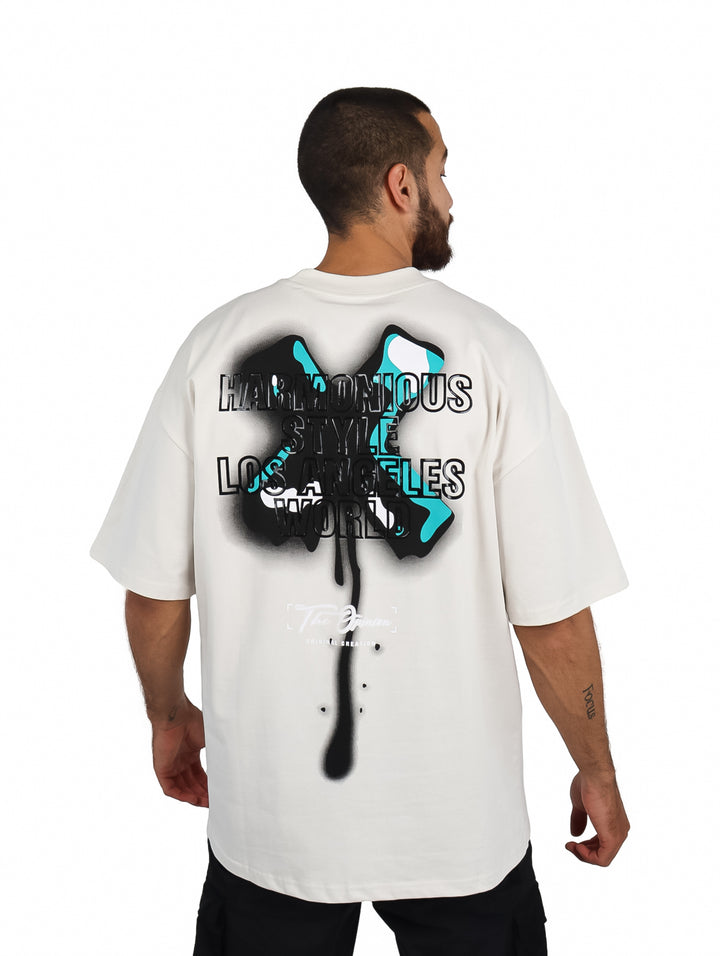 Hombre vistiendo playera oversize color beige con logotipo pequeño en el pecho.