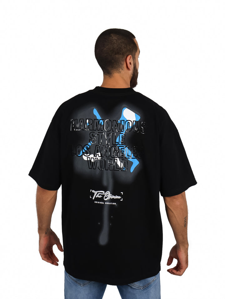 Hombre vistiendo playera oversize color negro con logo azul en el pecho.