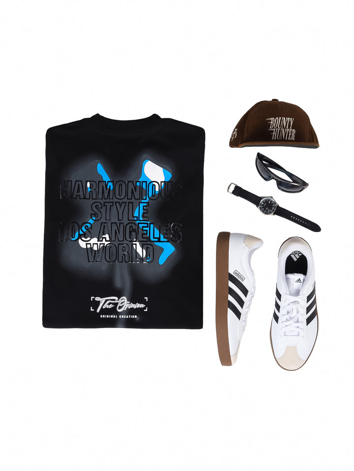 Hombre vistiendo playera oversize color negro con logo azul en el pecho.