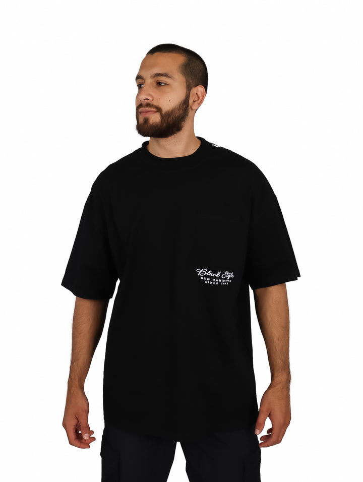 Hombre vistiendo una playera oversize de color negro con cuello redondo y manga corta.