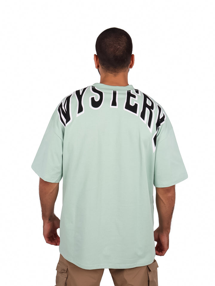 Hombre vistiendo playera oversize color menta con bolsillo frontal y cuello redondo.