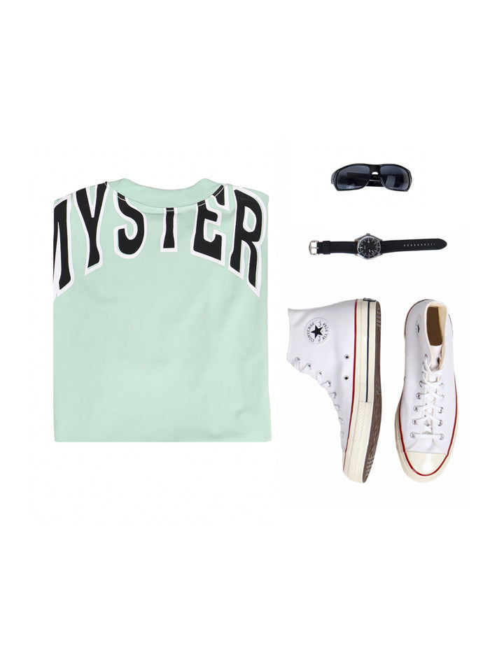Hombre vistiendo playera oversize color menta con bolsillo frontal y cuello redondo.