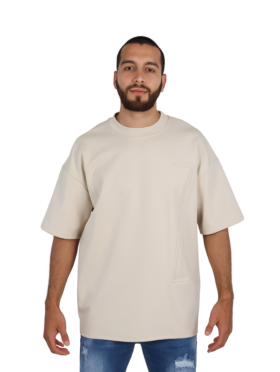 Hombre vistiendo playera oversize color beige de manga corta y cuello redondo.
