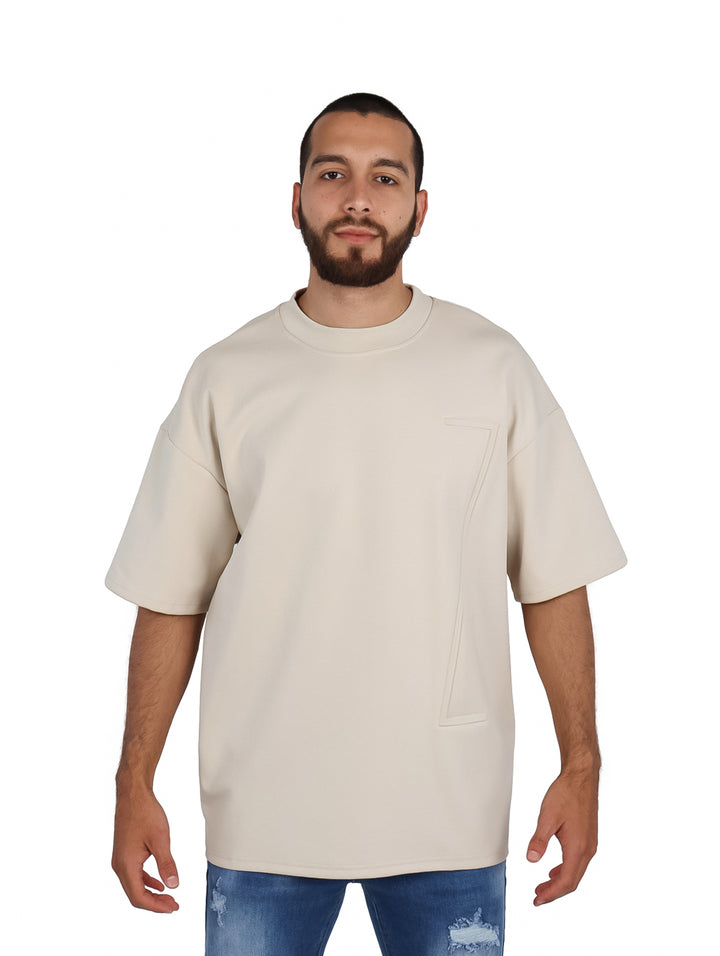 Hombre vistiendo playera oversize color beige de manga corta y cuello redondo.