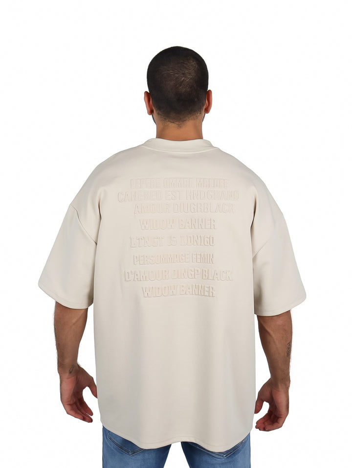 Hombre vistiendo playera oversize color beige de manga corta y cuello redondo.