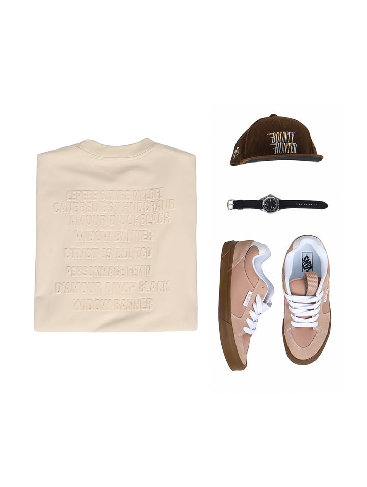 Hombre vistiendo playera oversize color beige de manga corta y cuello redondo.