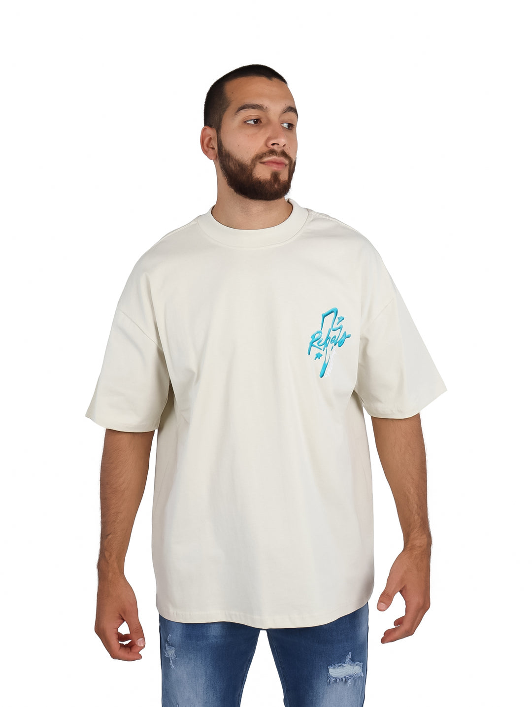 Hombre vistiendo playera oversize color arena con logo azul en el pecho.