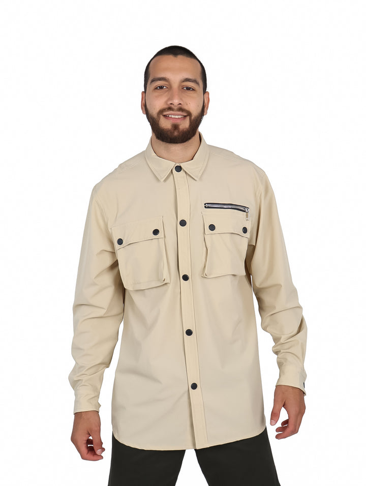Hombre vistiendo camisa oversize color khaki de manga larga con bolsillos frontales y botones negros.