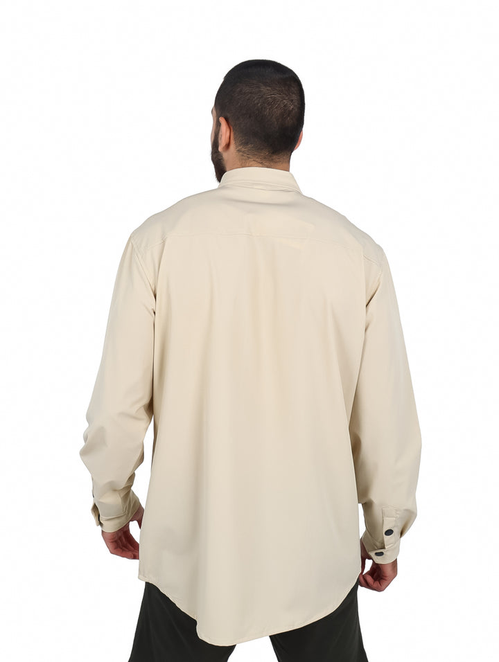 Hombre vistiendo camisa oversize color khaki de manga larga con bolsillos frontales y botones negros.