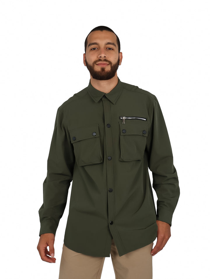 Hombre vistiendo camisa oversize color verde oliva con bolsillos frontales y manga larga.