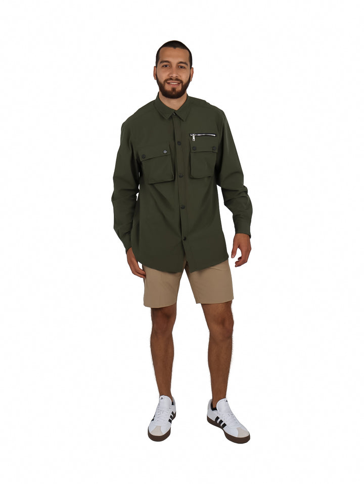 Hombre vistiendo camisa oversize color verde oliva con bolsillos frontales y manga larga.