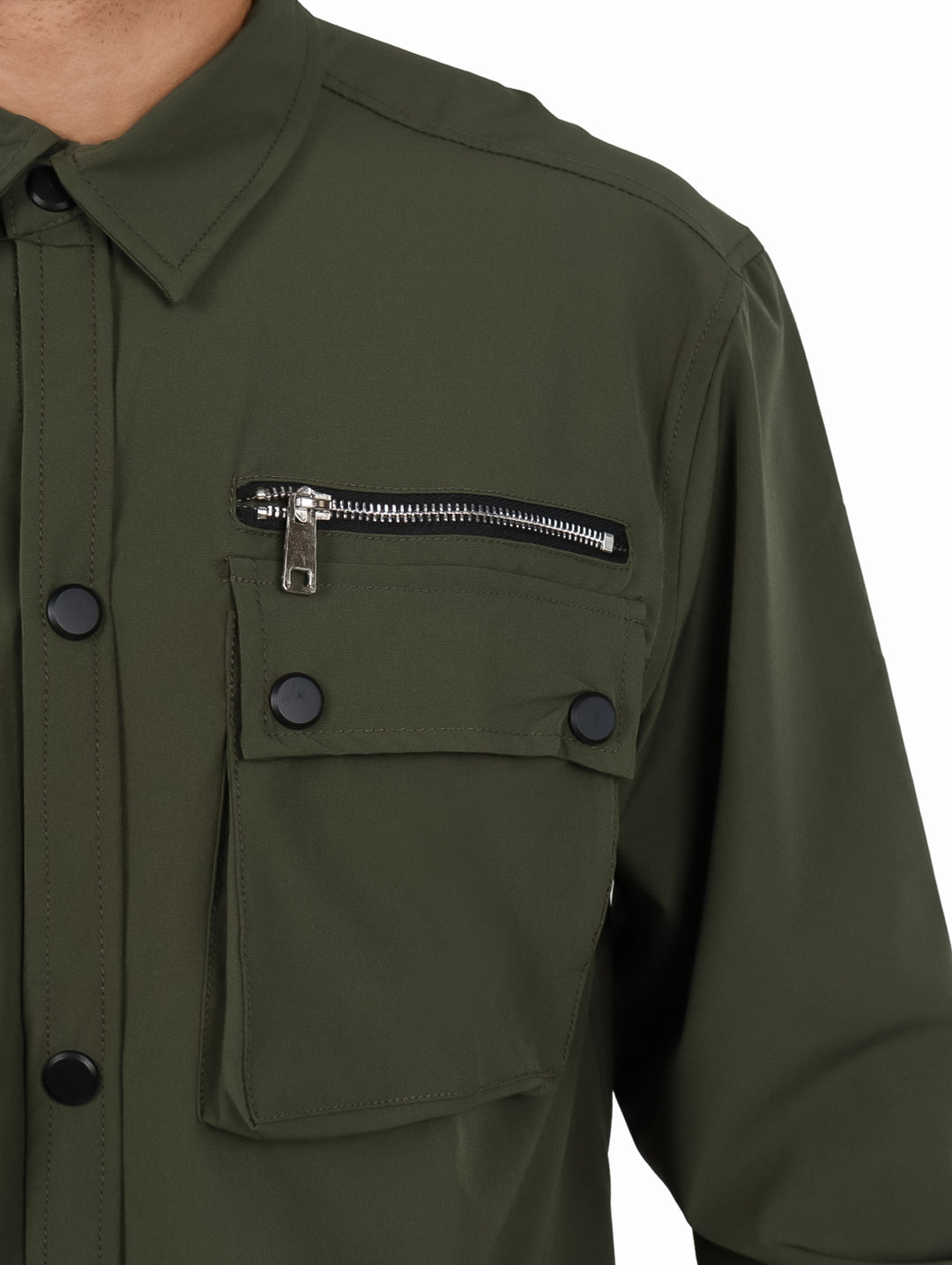 Hombre vistiendo camisa oversize color verde oliva con bolsillos frontales y manga larga.