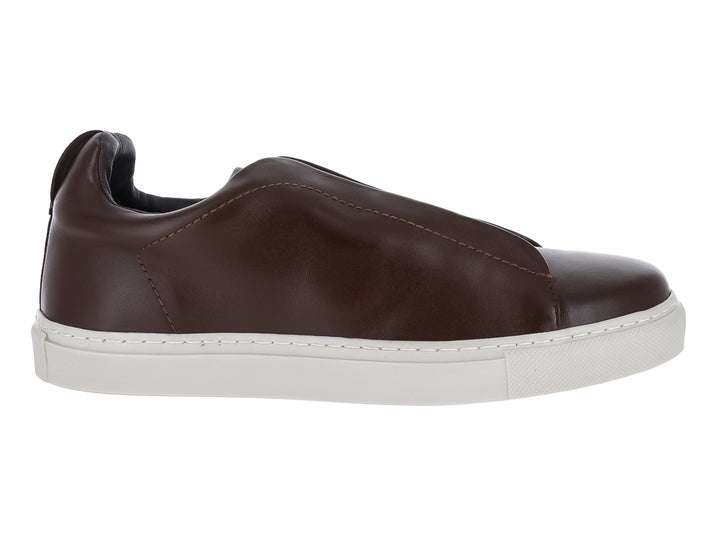 Zapato casual slip-on de cuero color café con suela blanca plana.