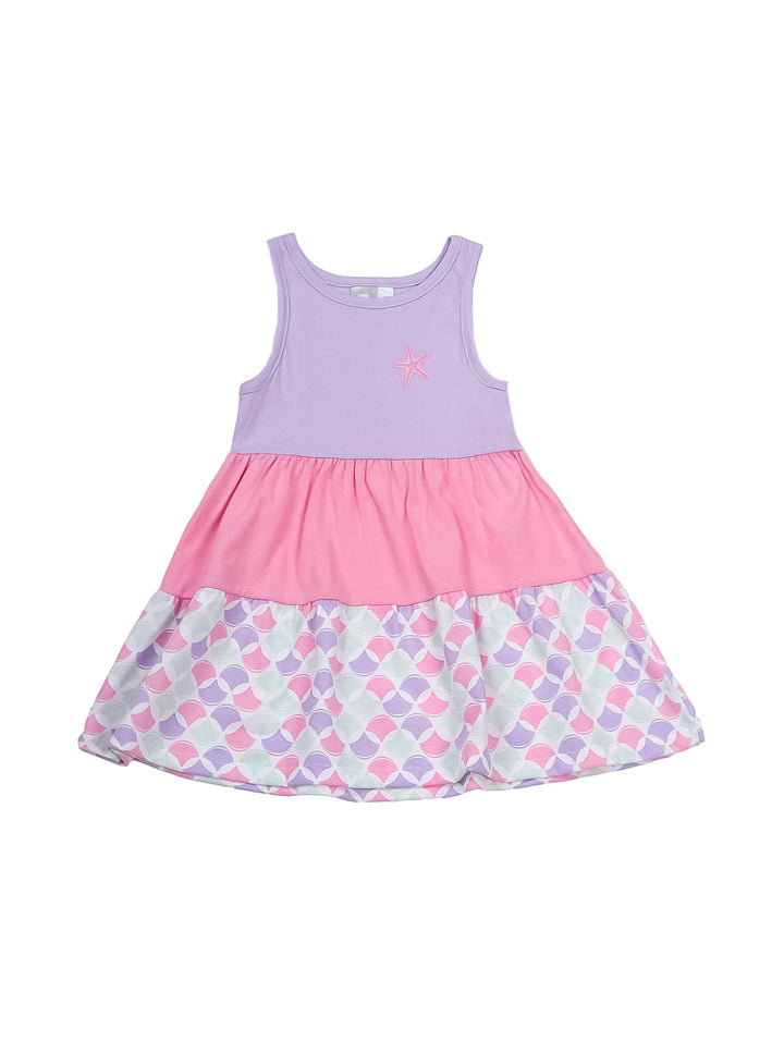 Niña pequeña con vestido casual en tonos lila y rosa con estampado de escamas en el borde inferior.