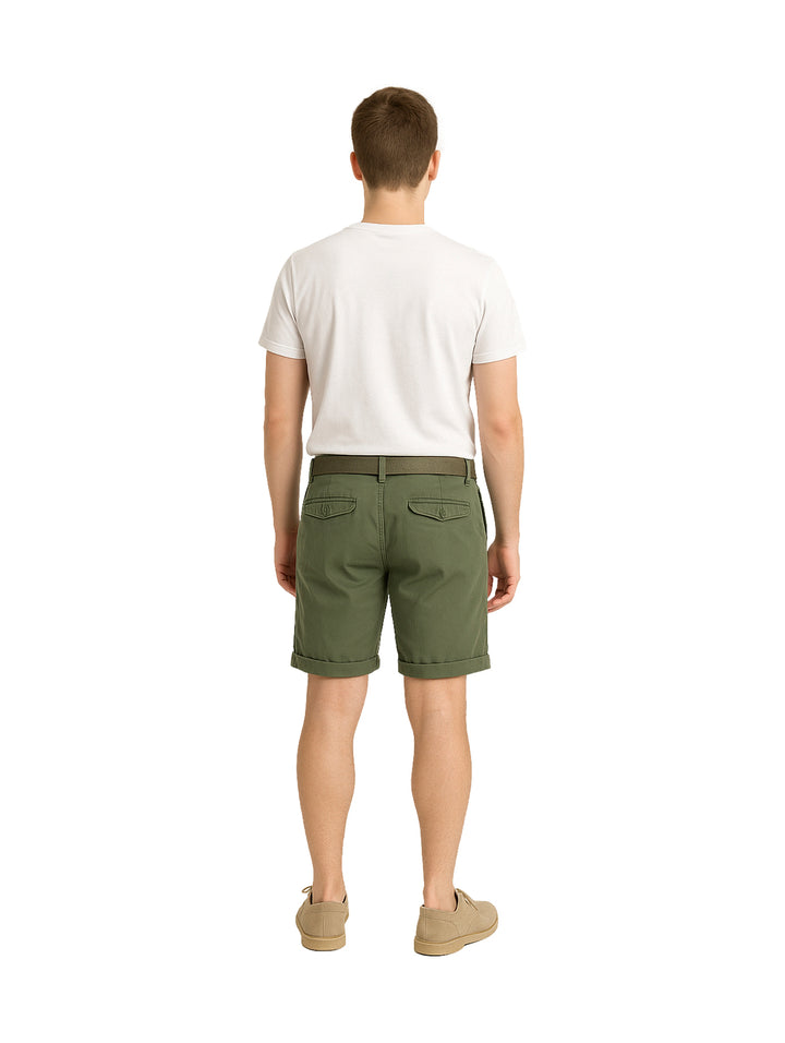 Hombre modelando bermudas color verde militar con playera blanca y zapatos beige sobre fondo blanco.