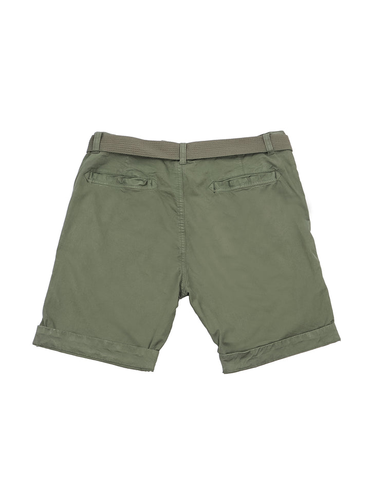 Hombre modelando bermudas color verde militar con playera blanca y zapatos beige sobre fondo blanco.