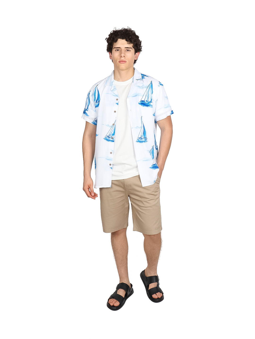 Hombre vistiendo camisa blanca de manga corta con estampado de veleros azules.