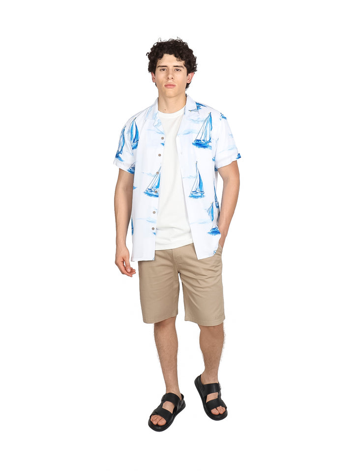 Hombre vistiendo camisa blanca de manga corta con estampado de veleros azules.