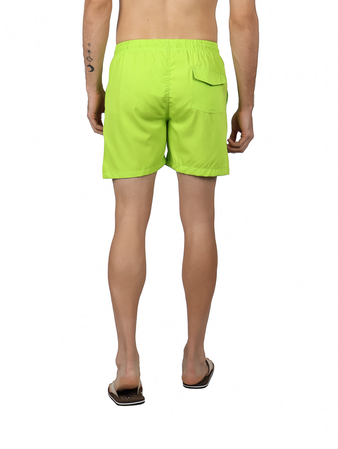 Hombre vistiendo un traje de baño tipo short en color verde neón con cintura elástica y cordón.