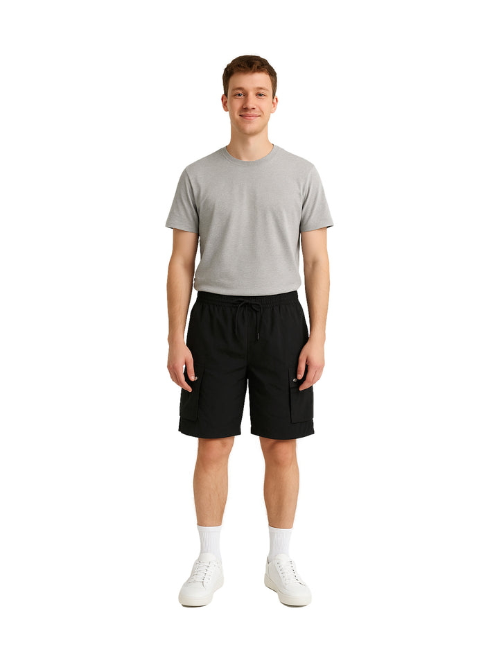 Hombre vistiendo shorts de surf color negro con bolsillos laterales.