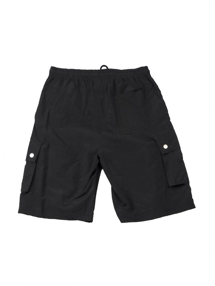 Hombre vistiendo shorts de surf color negro con bolsillos laterales.