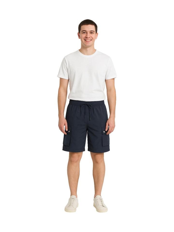 Hombre vistiendo shorts de surf color marino con bolsillos laterales y camiseta blanca.