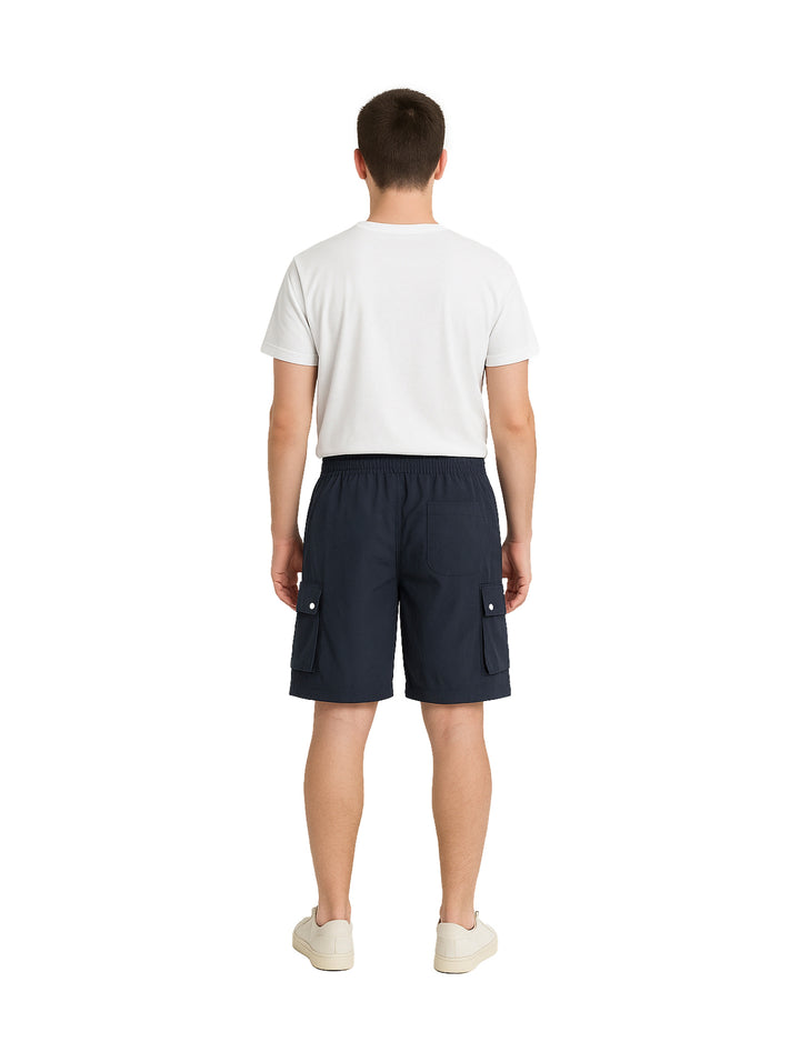 Hombre vistiendo shorts de surf color marino con bolsillos laterales y camiseta blanca.