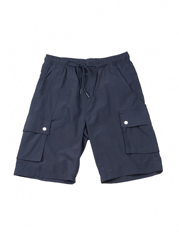 Hombre vistiendo shorts de surf color marino con bolsillos laterales y camiseta blanca.