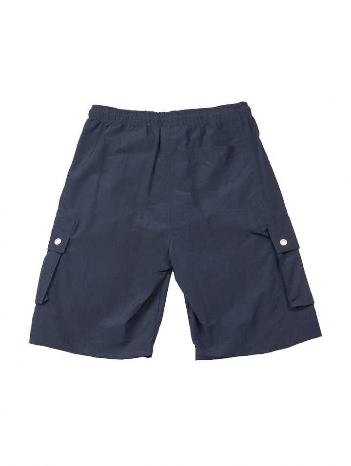 Hombre vistiendo shorts de surf color marino con bolsillos laterales y camiseta blanca.