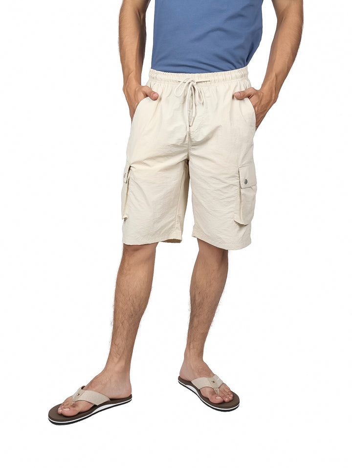 Hombre vistiendo shorts cargo color off white con cordón ajustable y bolsillos laterales.