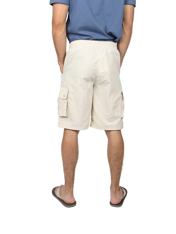 Hombre vistiendo shorts cargo color off white con cordón ajustable y bolsillos laterales.