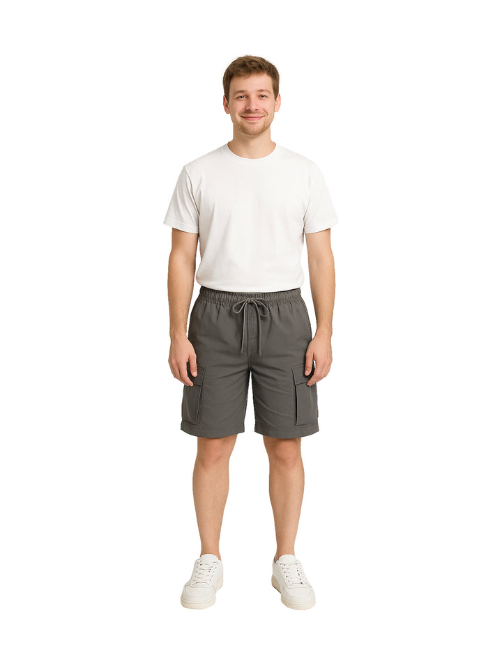 Hombre vistiendo shorts de surf color gris con bolsillos laterales y camiseta blanca.