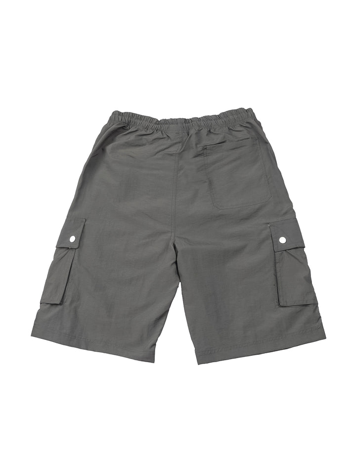 Hombre vistiendo shorts de surf color gris con bolsillos laterales y camiseta blanca.