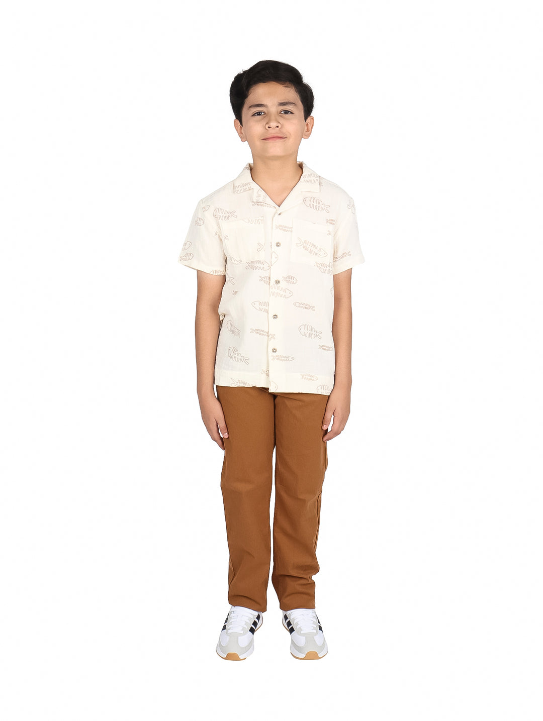 Niño vistiendo una camisa de manga corta color beige claro con estampado de peces.