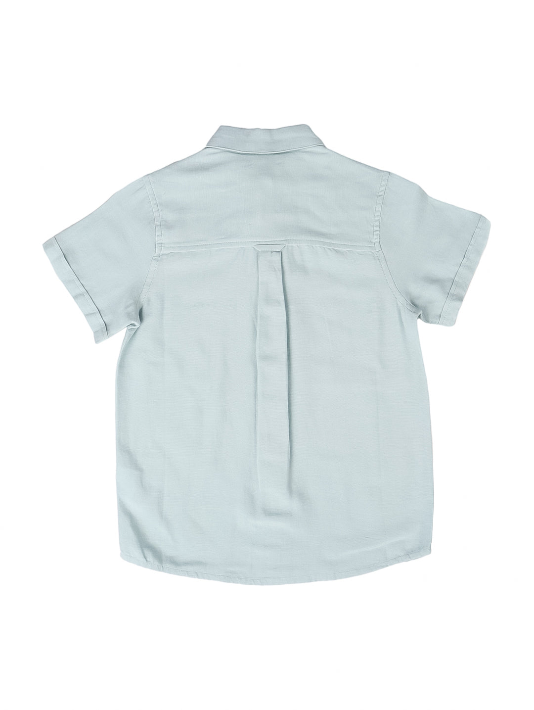 Camisa de lino color azul claro para niño, con manga corta y cierre frontal de botones.