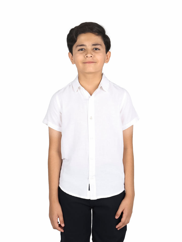Niño vistiendo una camisa de lino color blanco de manga corta y cuello clásico.