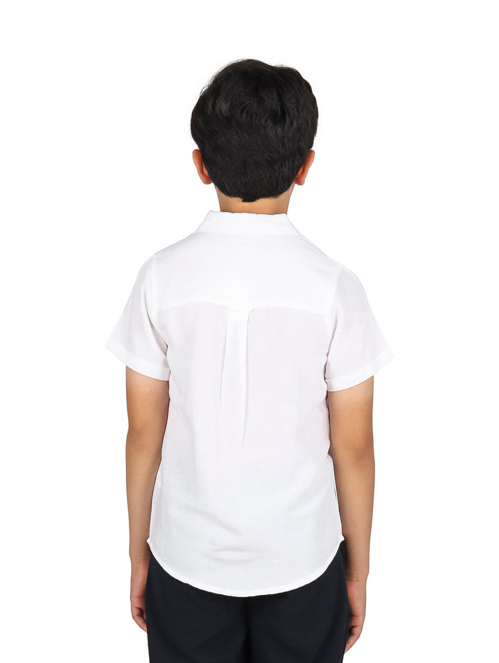 Niño vistiendo una camisa de lino color blanco de manga corta y cuello clásico.