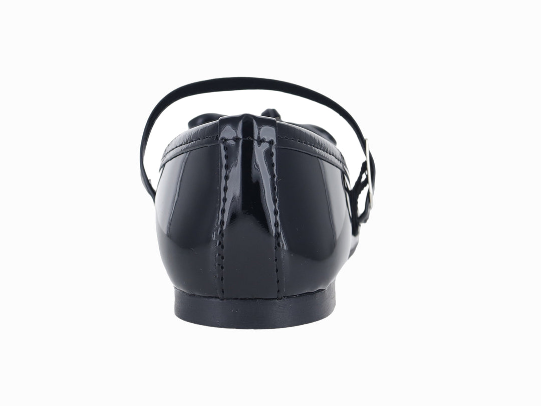 Zapato plano negro de charol para niña con correa, hebilla y moño decorativo en la punta.