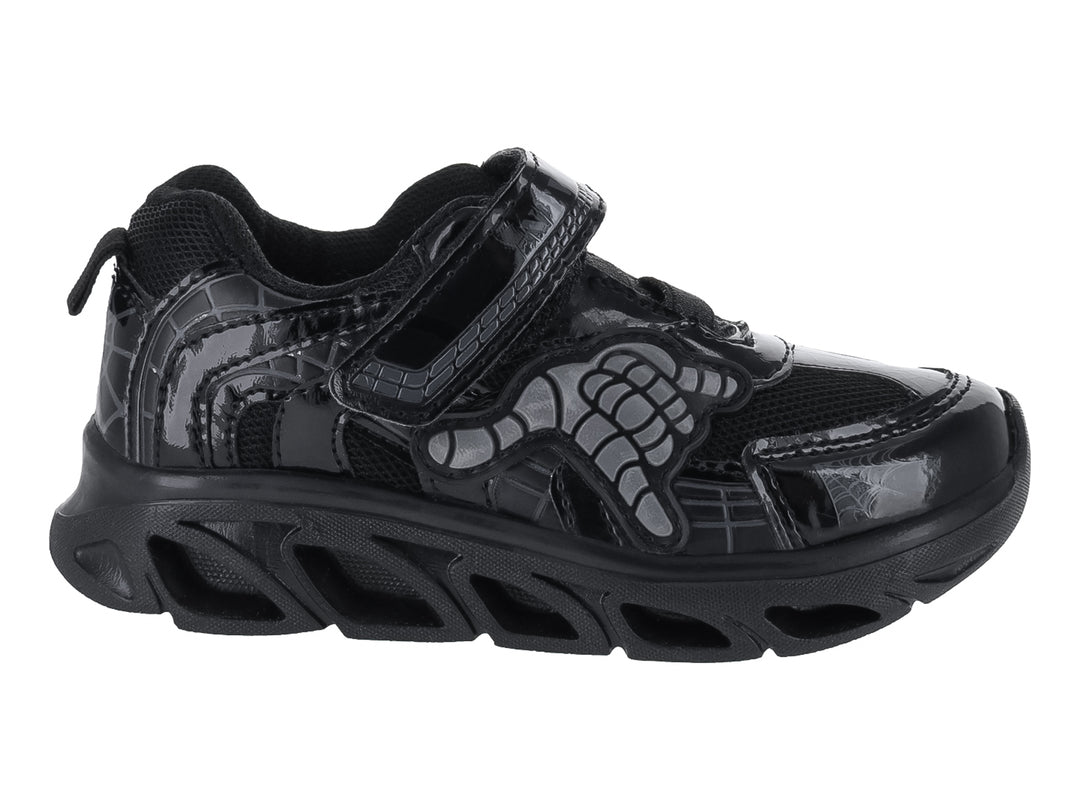 Tenis deportivos negros para niño con diseño de hueso en el lateral y cierre de velcro.