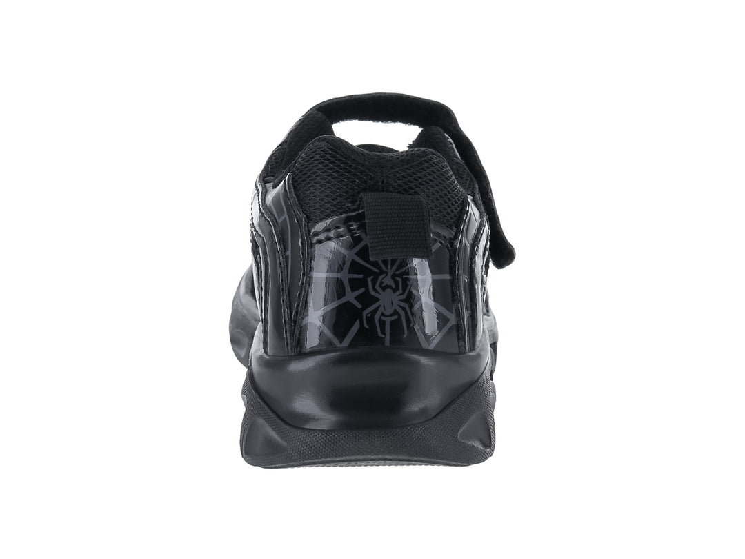 Tenis deportivos negros para niño con diseño de hueso en el lateral y cierre de velcro.