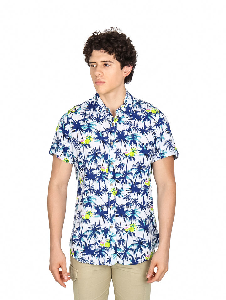 Hombre vistiendo camisa hawaiana blanca con estampado de palmeras azules y verdes.