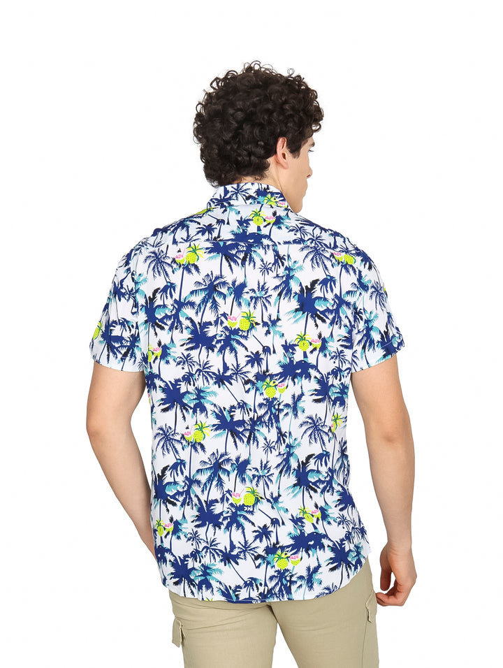 Hombre vistiendo camisa hawaiana blanca con estampado de palmeras azules y verdes.