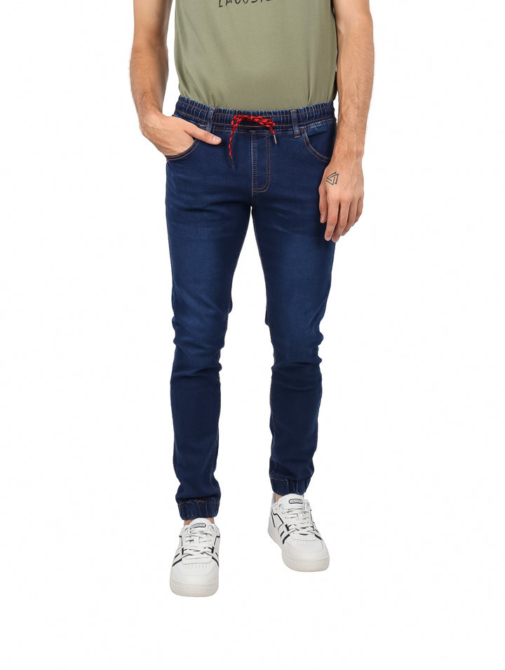 Hombre vistiendo jeans jogger color índigo con cintura elástica y cordón rojo.