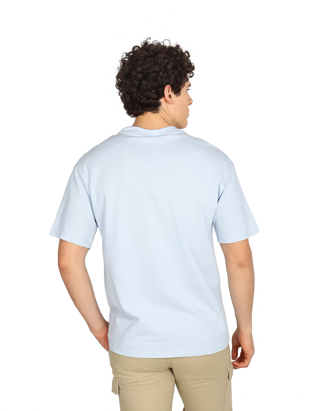 Hombre vistiendo una playera oversize de color azul claro con cuello redondo y manga corta.