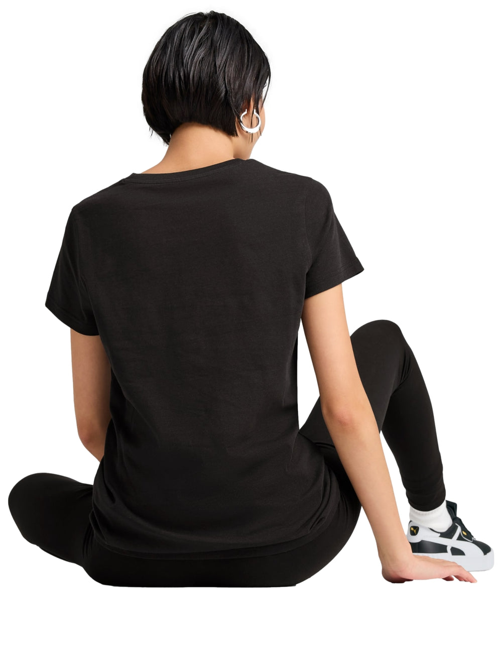 Mujer vistiendo una camiseta deportiva PUMA de color negro con logotipo dorado metálico en el pecho.