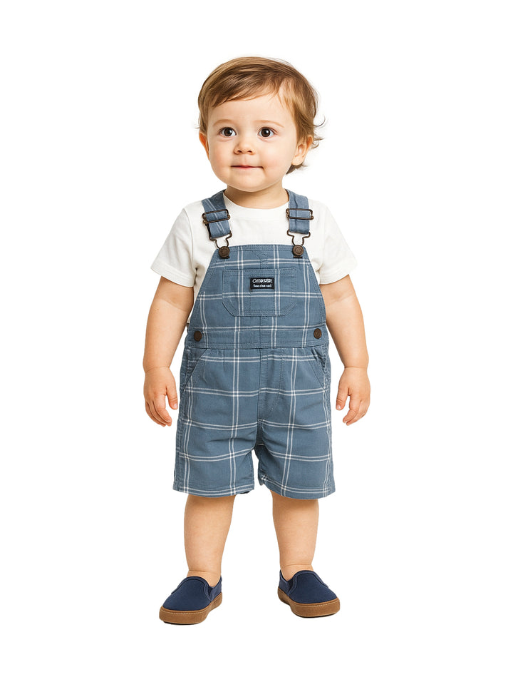 Niño pequeño usando un overol color acero a cuadros con camiseta blanca.