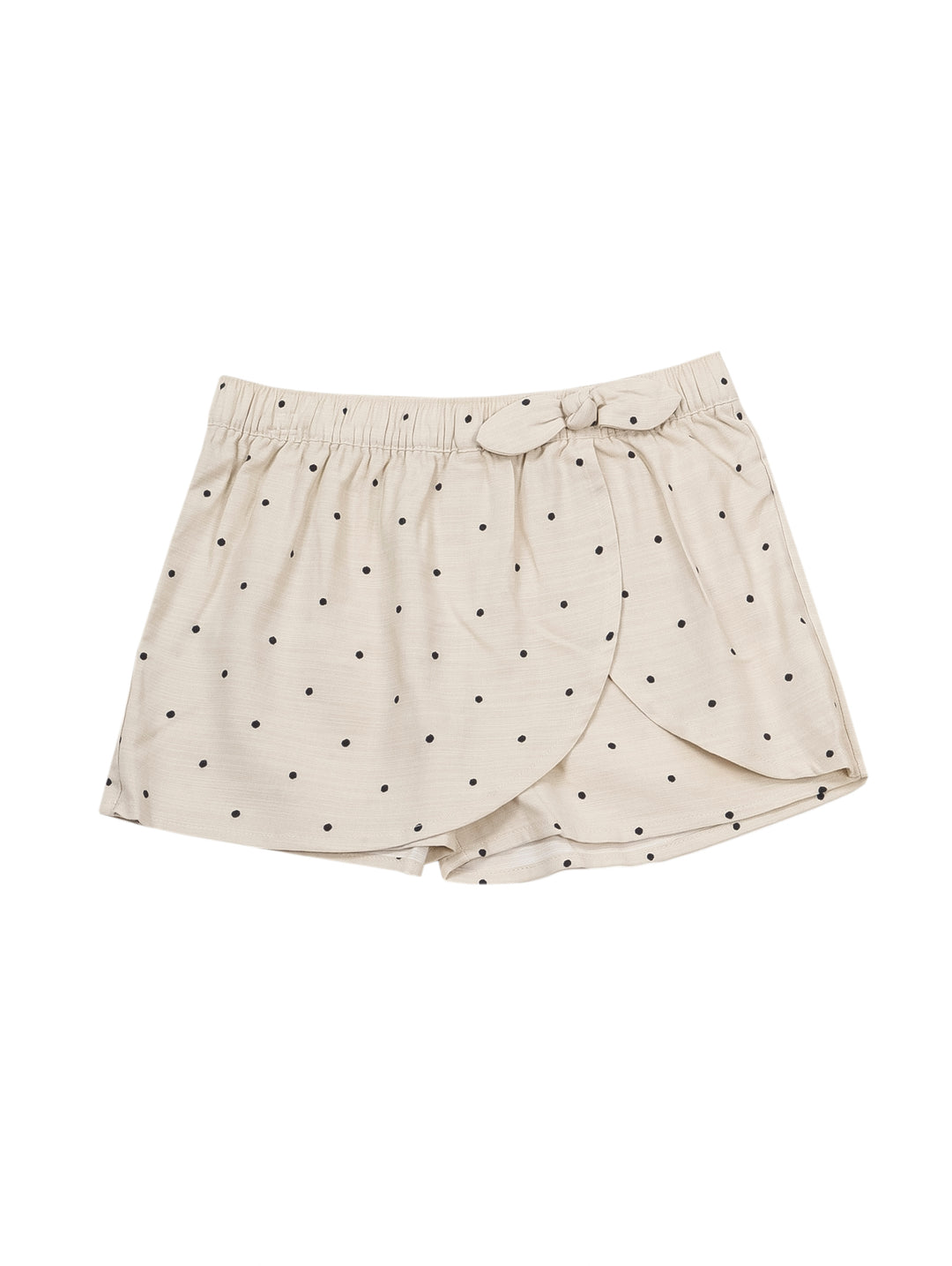 Niña vistiendo un short falda color beige con lunares oscuros y un lazo en la cintura.