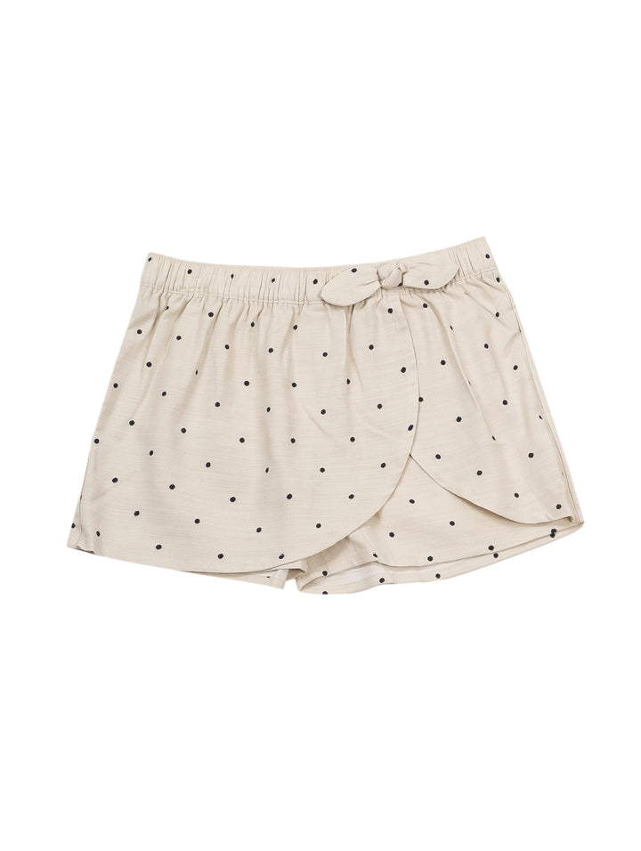 Niña vistiendo un short falda color beige con lunares oscuros y un lazo en la cintura.