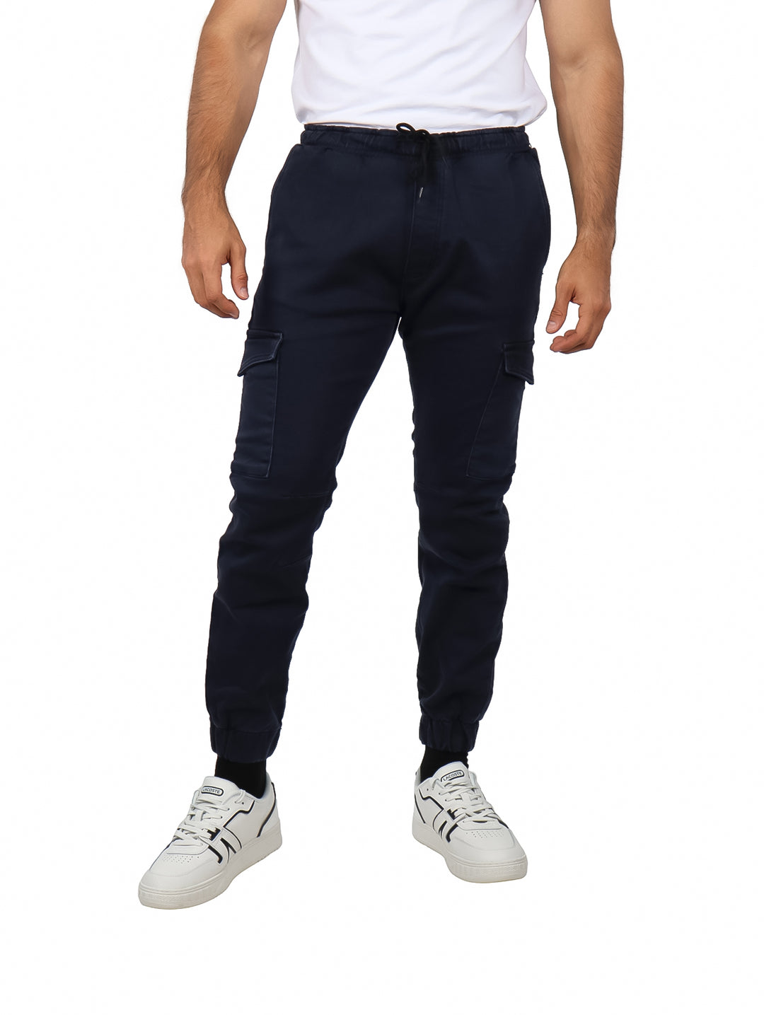 Hombre vistiendo pantalones jogger color azul marino con bolsillos laterales y calzado blanco.